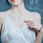 Close-up of an Asian woman in a white dress showcasing elegant necklace and bracelets.